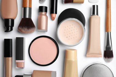 Beyaz zemin üzerinde yüz pudraları ve diğer dekoratif kozmetik ürünler düz yatıyordu