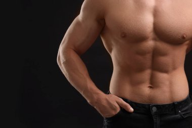 Kaslı adam siyah arka planda kaslarını gösteriyor, yakın plan ve mesaj için boşluk. Seksi vücut.