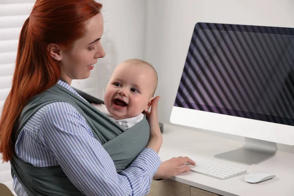 Mother Holding Her Child Sling Baby Carrier While Using Computer — Stock Photo, Image