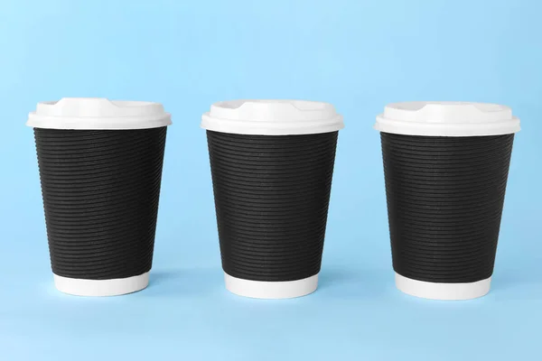 Paper cups with white lids on light blue background. Coffee to go