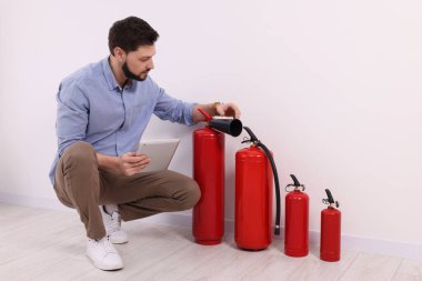 Man with tablet checking fire extinguishers indoors clipart