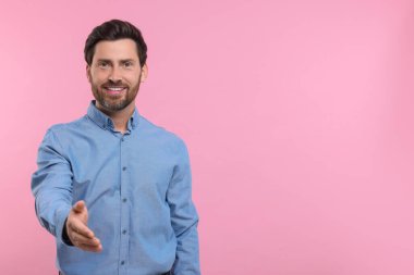 Mutlu adam karşılama ve pembe arka planda el sıkışma teklif ediyor. Metin için boşluk