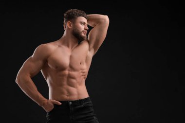 Siyah arka planda yakışıklı kaslı adam, mesaj için yer var. Seksi vücut.