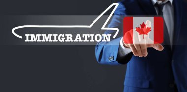 Göçmen bürosu. İş adamı dijital ekrana dokunuyor. Koyu gri arka planda Kanada 'nın uçak, kelime ve bayrağını gösteriyor. Yakın plan.