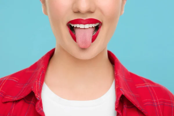 stock image Woman showing her tongue on light blue background, closeup