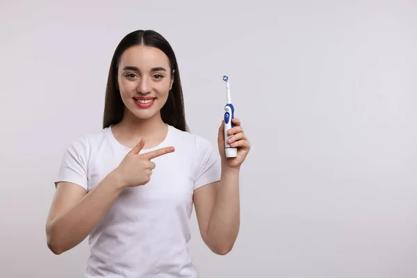 Ευτυχισμένη Νεαρή Γυναίκα Κρατώντας Ηλεκτρική Οδοντόβουρτσα Λευκό Φόντο Χώρος Για — Φωτογραφία Αρχείου