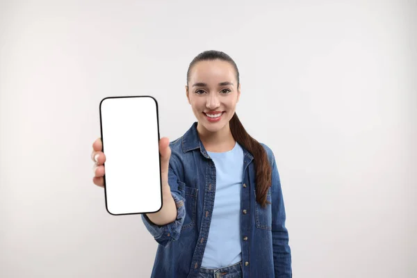 Νεαρή Γυναίκα Δείχνει Smartphone Στο Χέρι Λευκό Φόντο — Φωτογραφία Αρχείου