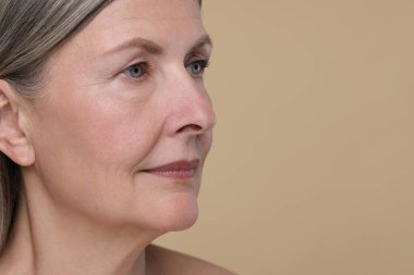 Bej arka planda yaşlanmakta olan yaşlı kadın portresi, yazı için yer. Yenilenme tedavisi