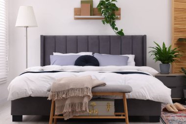 Çift kişilik yatağı ve güzel yeşil çiçekleri olan şık bir yatak odası. Modern iç mimari