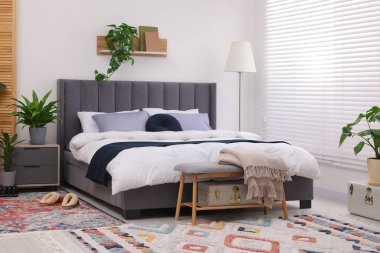 Çift kişilik yatağı ve güzel yeşil çiçekleri olan şık bir yatak odası. Modern iç mimari