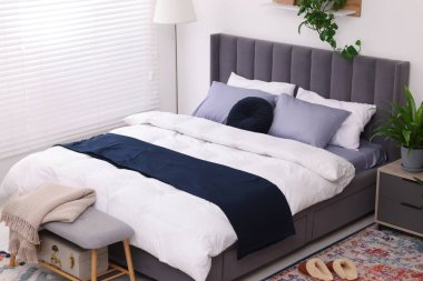 Çift kişilik yatağı ve güzel yeşil çiçekleri olan şık bir yatak odası. Modern iç mimari