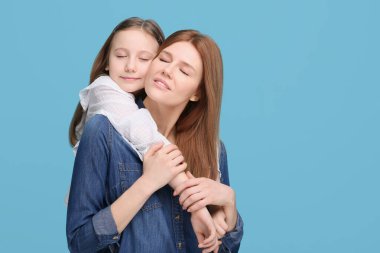 Açık mavi arka planda mutlu anne ve tatlı kızının portresi. Metin için boşluk
