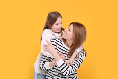 Turuncu arka planda mutlu anne ve tatlı kızının portresi.