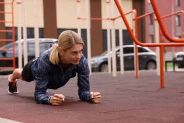 Açık spor salonunda tahta egzersizi yapan bir kadın, mesaj atmak için yer var.