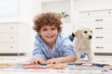 Küçük çocuk evde tatlı bir köpek yavrusuyla yatıyor.