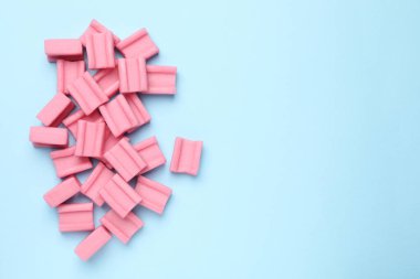 Açık mavi arka planda leziz pembe sakızlar, düz uzanış. Metin için boşluk