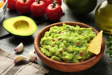 Gri masadaki cips ve malzemelerle nefis guacamole sosu.