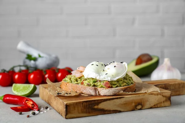 Delicious sandwich with guacamole, shrimps and fried egg on light grey table. Space for text