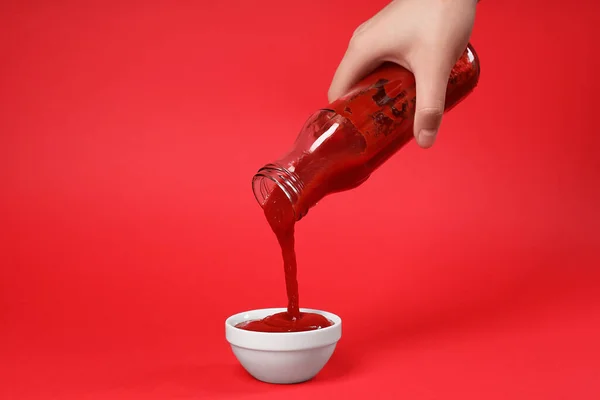 Mujer Vertiendo Sabroso Ketchup Botella Tazón Sobre Fondo Rojo Primer — Foto de Stock