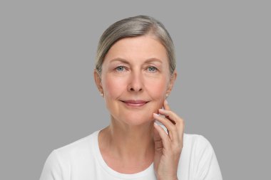 Gri arka planda yaşlanan yaşlı bir kadının portresi. Yenilenme tedavisi