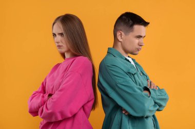 Turuncu arka planda çapraz kollu kızgın bir çiftin portresi