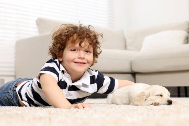 Evdeki bej halıda şirin köpek yavrusu olan küçük çocuk.