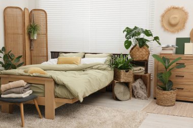 Rahat bir yatak ve yatak odasında güzel yeşil bitkiler.