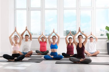 Paspaslar üzerinde yoga yapan bir grup insan.