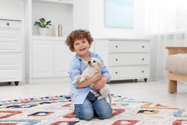 Evdeki halıda sevimli köpek yavrusu olan küçük çocuk.