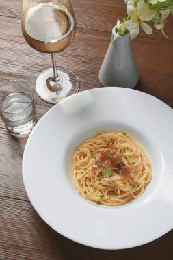 Prosciutto ve mikroyeşillikli lezzetli spagetti ahşap masada servis edilir, manzaranın üstünde. Makarna yemeğinin enfes sunumu