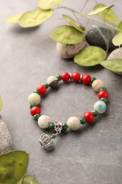 Beautiful bracelet with gemstones, leaves and stones on grey background