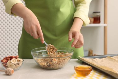 Mutfaktaki açık mermer masada granola yapan kadın, yakın plan.
