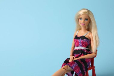 Mykolaiv, Ukrayna - 4 Eylül 2023: Açık mavi zemin üzerinde oturan güzel Barbie bebek, metin için yer