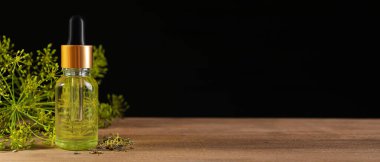 Ahşap masada siyah arka planda bir şişe dereotlu yağ. Metin için alanı olan pankart tasarımı