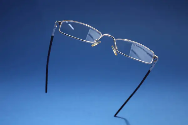 Mavi Arka Planda Metal Çerçeveli Şık Bir Gözlük — Stok fotoğraf