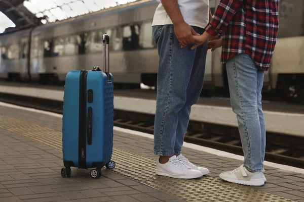 Long-distance relationship. Couple holding hands on platform of railway station, closeup
