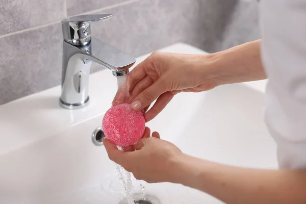 Young woman washing face sponge in bathroom, closeup