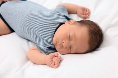 Sevimli yeni doğmuş bebek beyaz yumuşak yatakta uyuyor.