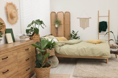 Rahat bir yatak ve yatak odasında güzel yeşil bitkiler.