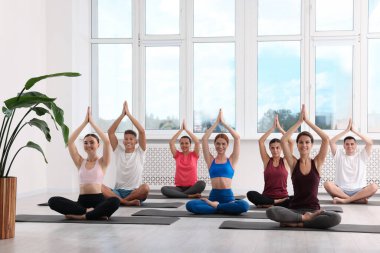 Paspaslar üzerinde yoga yapan bir grup insan.