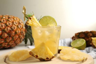 Lezzetli bir bardak ananas kokteyli ve masada dilimlenmiş meyve.