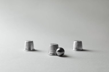 Metal yüksükler ve top açık gri arkaplanda. Thimblerig oyunu