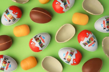 Sveti Vlas, Bulgaristan - 29 Haziran 2023: Açık yeşil zemin üzerinde Kinder Sürpriz Yumurtalar ve plastik kapsüller, düz yatar