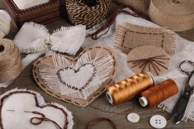 Çuval bezi parçaları, farklı dikişler ve ahşap masaya dikiş aletleri, yakın plan.