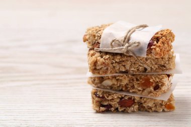 Beyaz ahşap masadaki lezzetli granola çubukları, yakın plan. Metin için boşluk