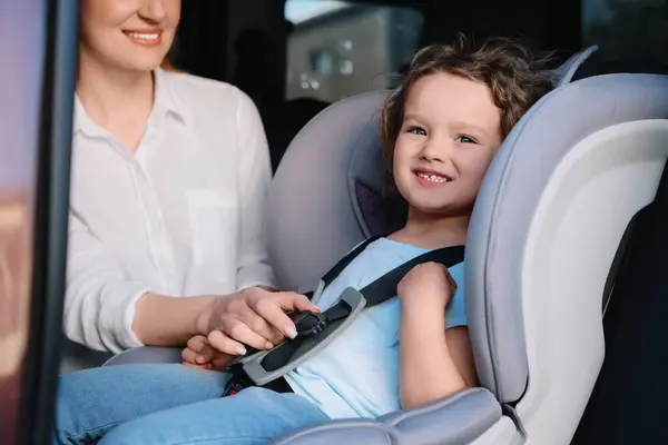 妈妈把女儿拴在车里的儿童安全座椅上 — 图库照片