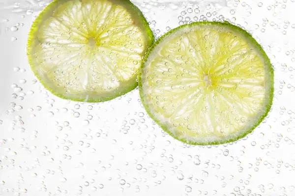 Juicy lime slices in soda water, closeup