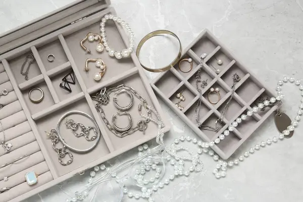 Jewelry boxes with many different accessories on light grey table, flat lay