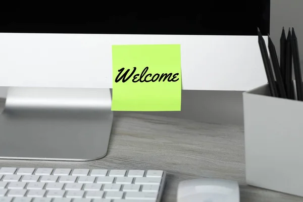 Sticky note with word Welcome on computer monitor in office