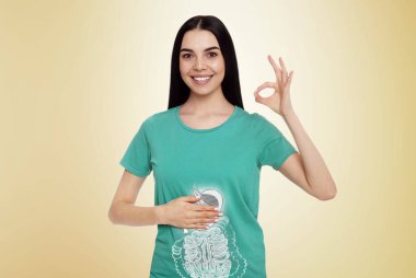 Açık sarı arka planda sağlıklı sindirim sistemi olan mutlu bir kadın. Gastrointestinal sistemin bir yansıması.